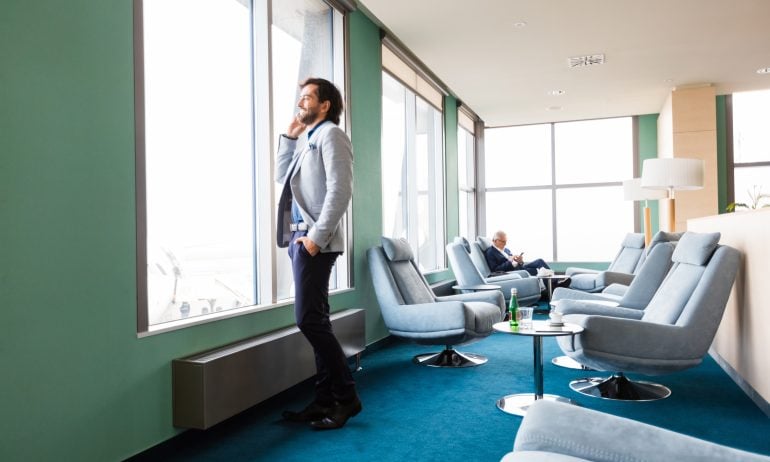 Businessman looking through window at airport lounge