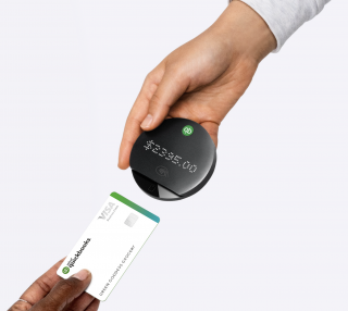 A customer holds a credit card up to the QuickBooks Card Reader