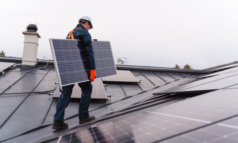 Worker installing solar panels on the roof.