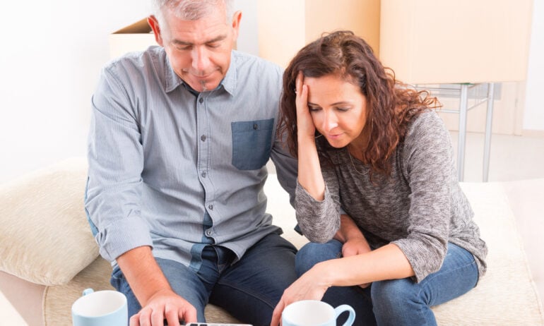 People looking at calculator and sitting on boxes.