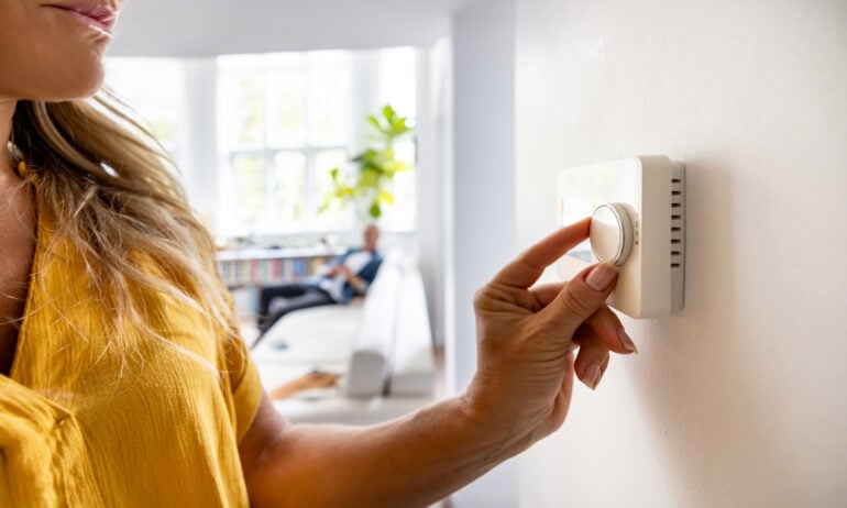 Person turning a thermostat