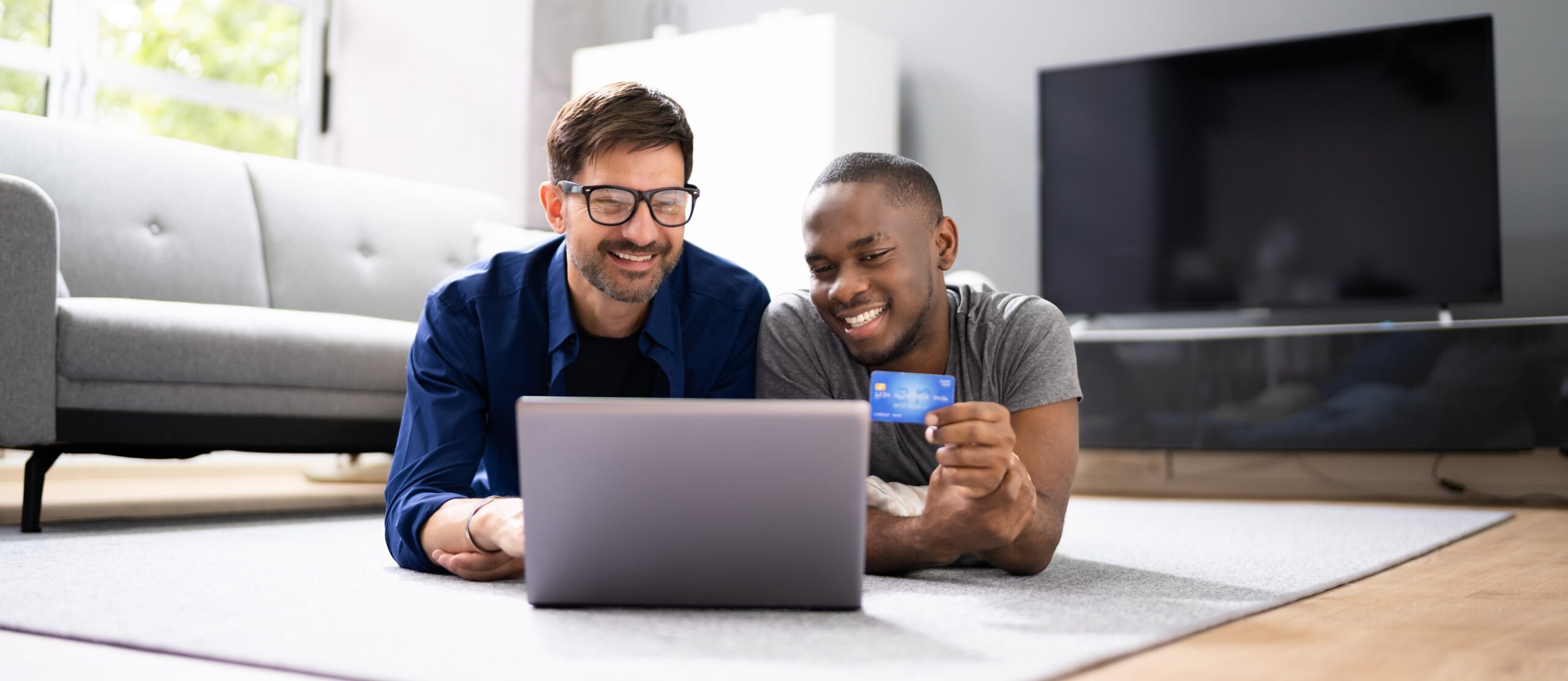 Two men use buy now pay later while shopping on their laptop.