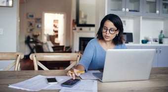 Woman dealing with finances on her laptop at kitchen table.