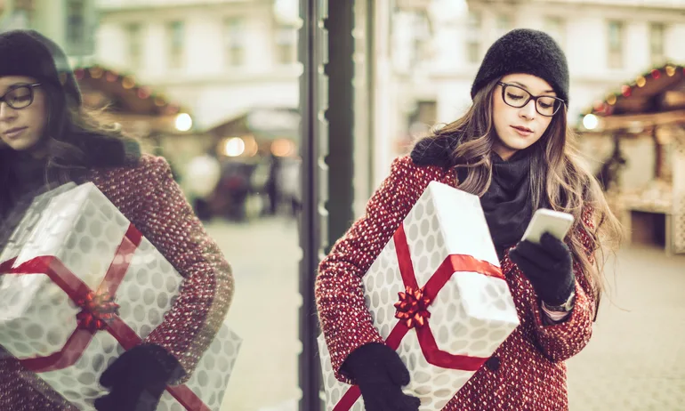 Holiday shopper checks her phone outside a store