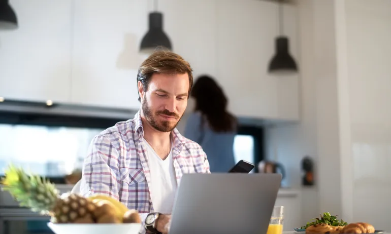 Man looking at laptop computer at kitchen table