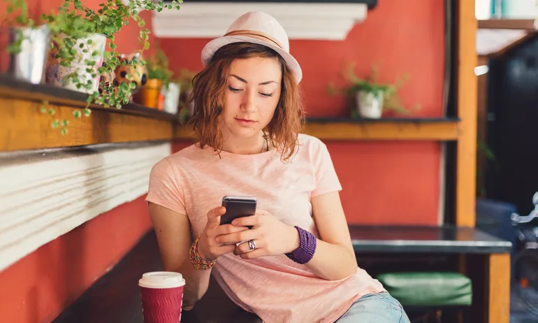 Young woman using cell phone in coffee shop