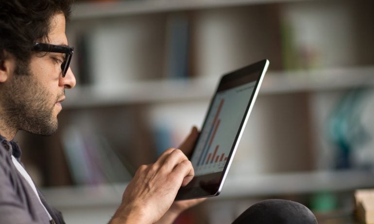 Young man looks at graph on tablet computer