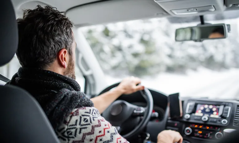 Man drives car on a snowy road.