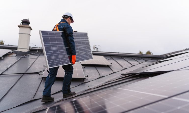 Worker installing solar panels on the roof.